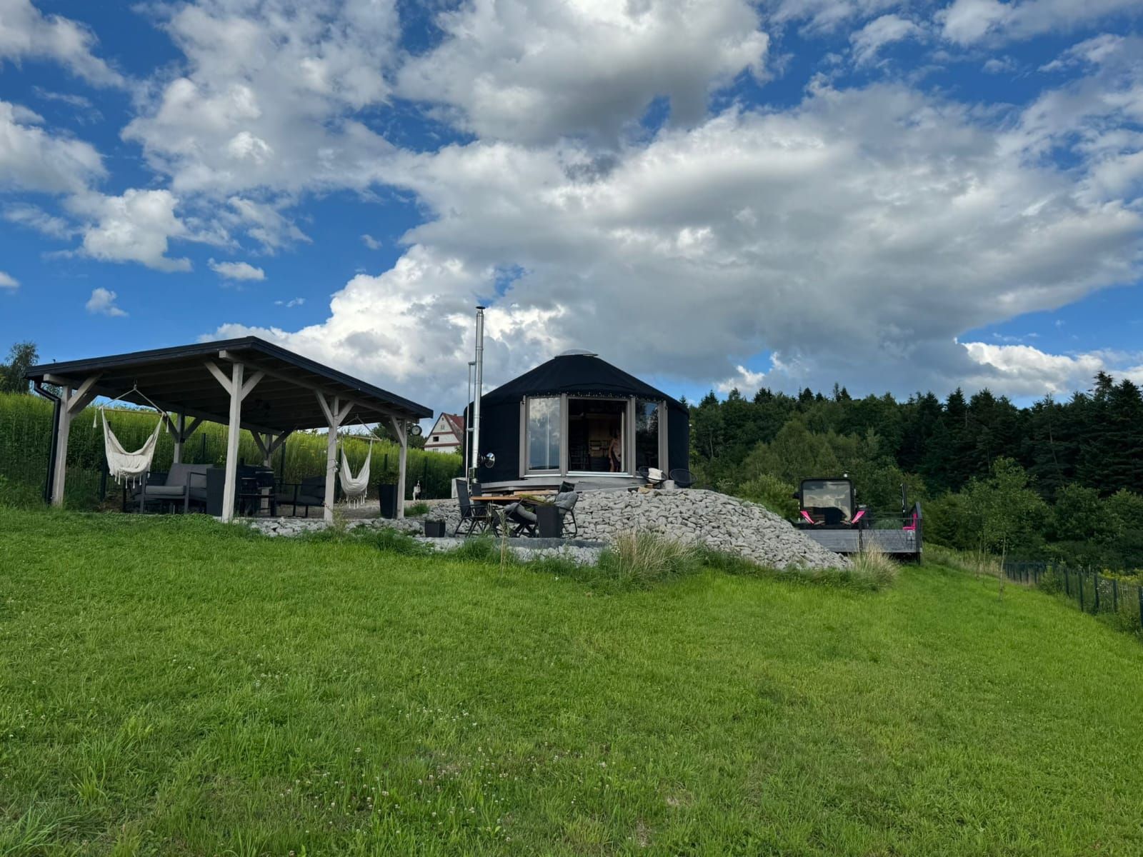 Jurta i pergola na zielonej łące nad jeziorem