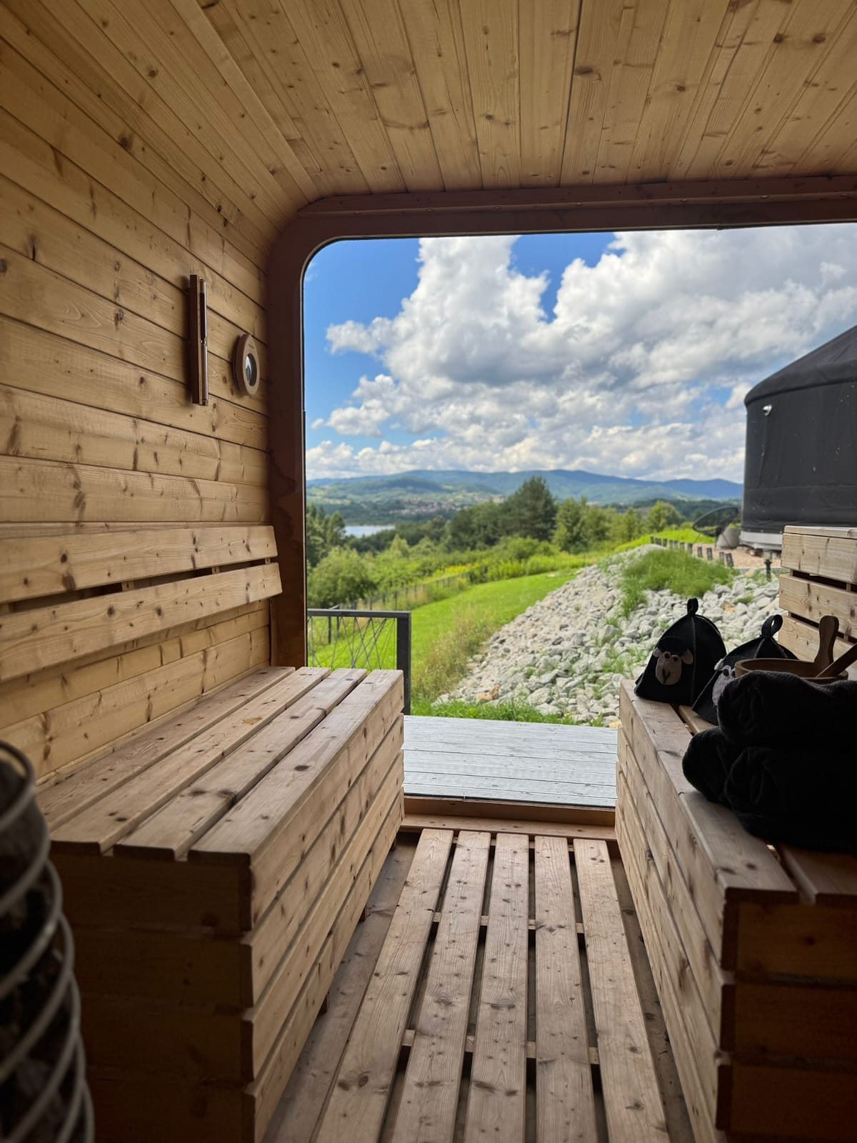 Wnętrze sauny z panoramicznym oknem na jezioro, góry i jurtę